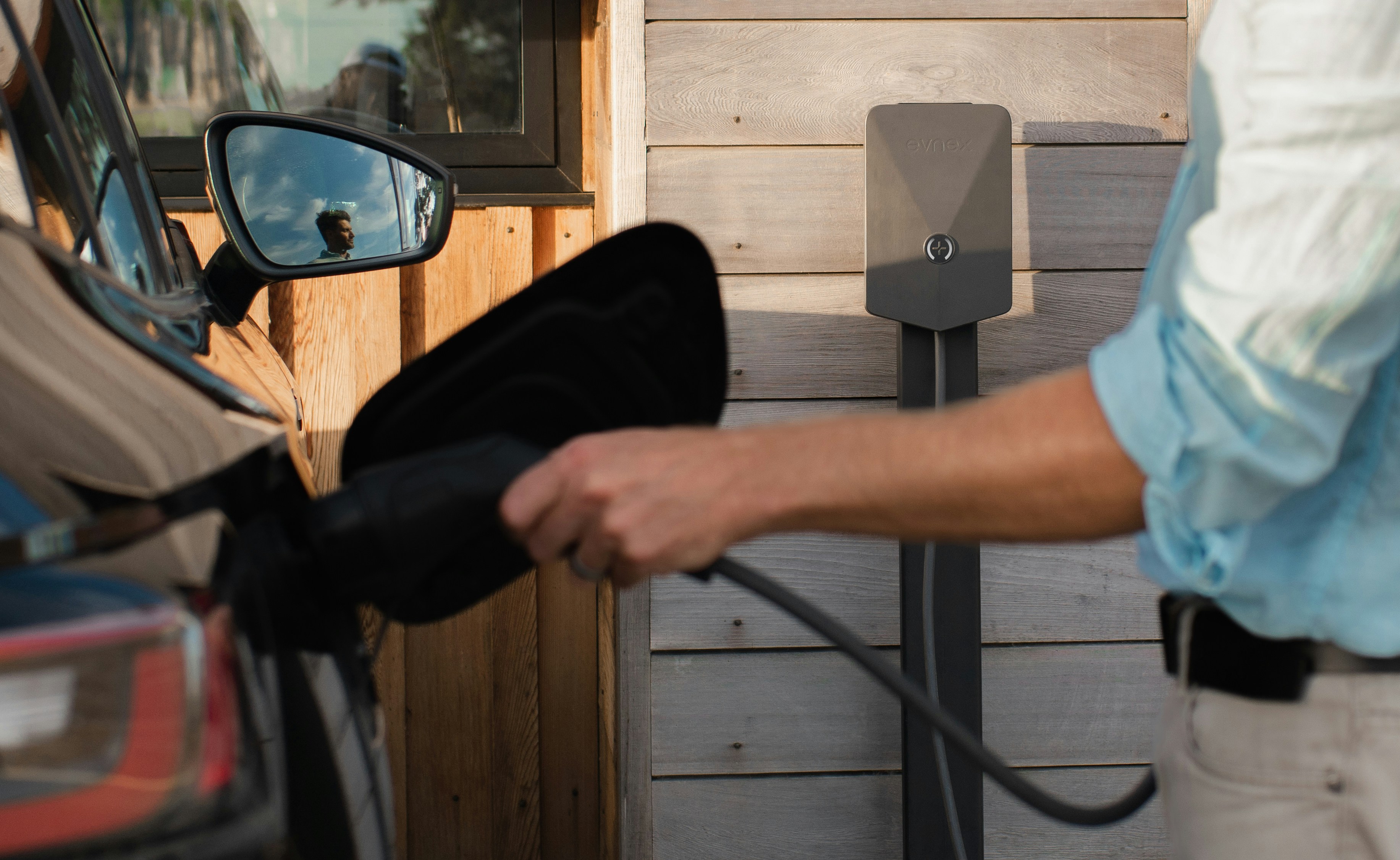 Persona conectando un automóvil a un cargador eléctrico residencial
